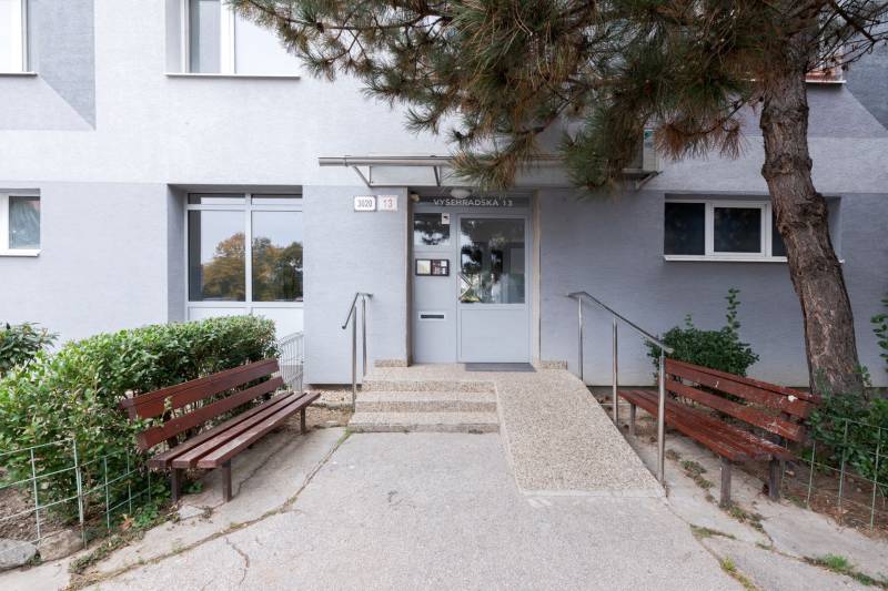 Entrance to the building on Vyšehradská Street in Bratislava - Petržalka with benches and greenery.