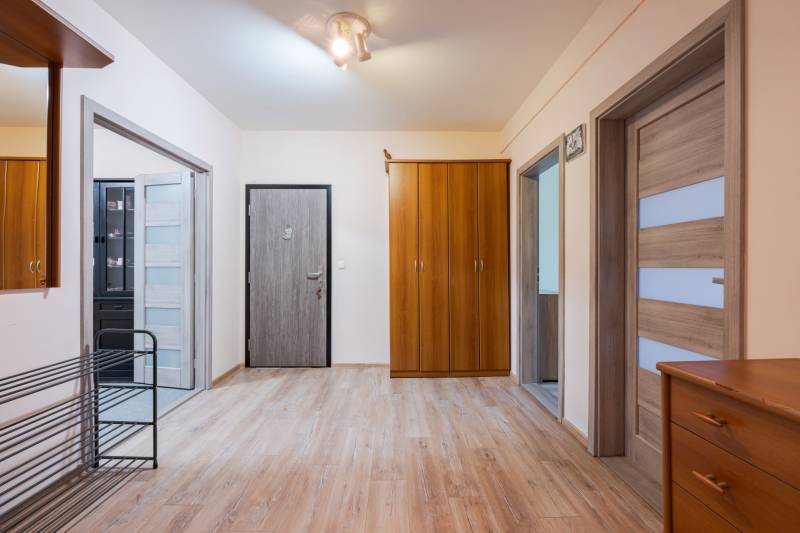 A hallway in a 4-room apartment with a wooden decor floor, a wardrobe, and a light.