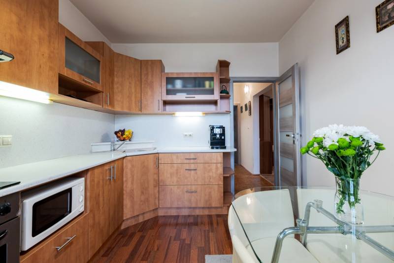 A kitchen with furnishings, flowers, and a floor with a wood decor in a 4-room apartment.