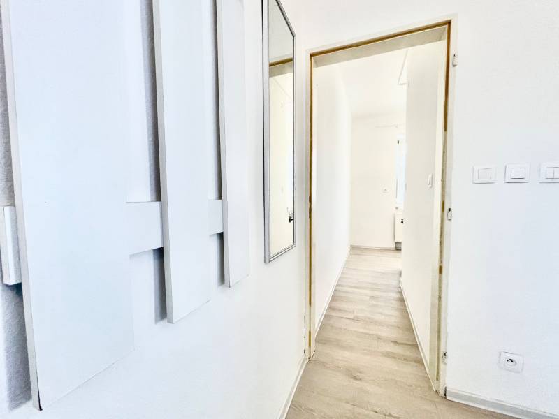 White interior with a hallway in a studio apartment and a wooden decor floor.