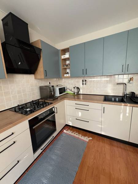 A kitchen in a 3-room apartment with tiled walls and a floor with a wooden design.