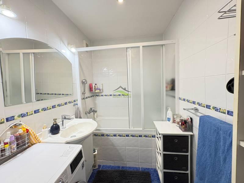 Bathroom in a 3-room apartment with a bathtub, shower, and washing machine, tiles with decor.