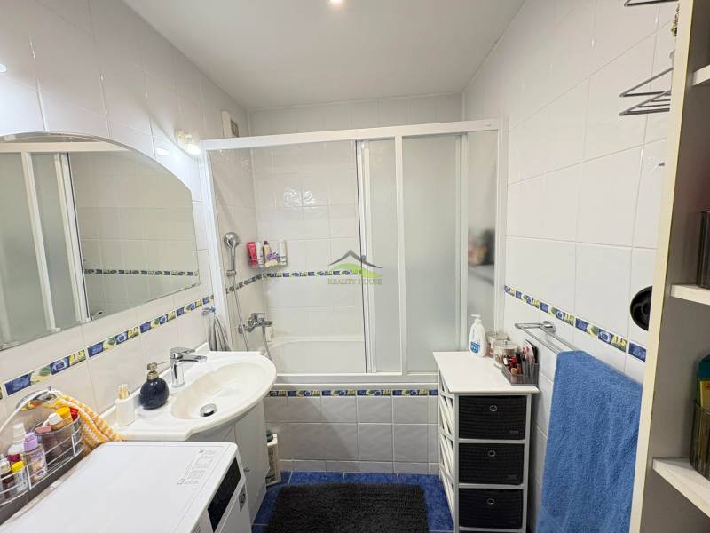 Bathroom in a 3-room apartment with a bathtub, sink, washing machine, and white tiles.