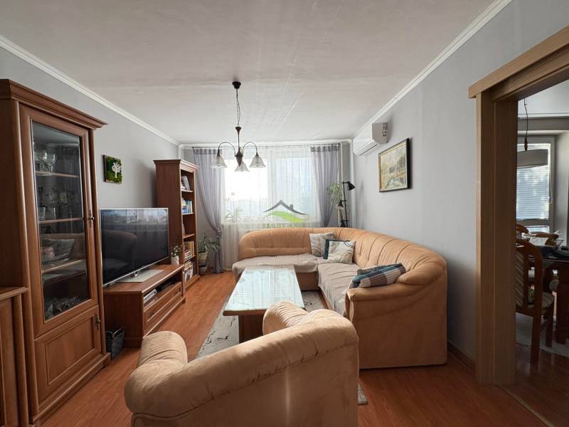 Living room with a comfortable sofa, wooden decor flooring, and pleasant lighting in a 3-room apartment.