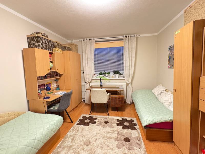A room in a 3-room apartment with a desk, a wooden-decor floor, and two beds.