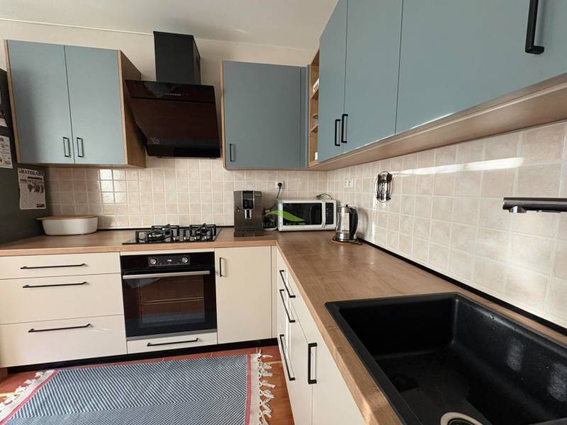 A kitchen unit in a 3-room apartment with a wooden decor floor and appliances.