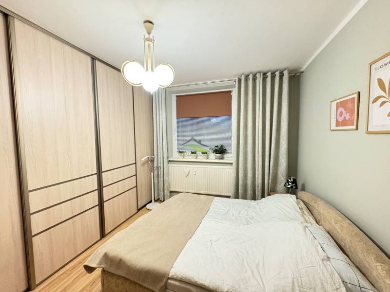 Bedroom with a bed, built-in wardrobe, and wooden decor flooring in a 3-room apartment.