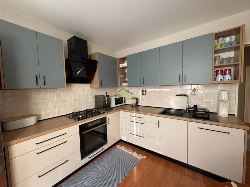 A kitchen in a 3-room apartment with a wooden decor floor and cooking equipment.