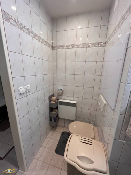 A bathroom in a 3-room apartment with a toilet, tiled with tiles and a trash can.