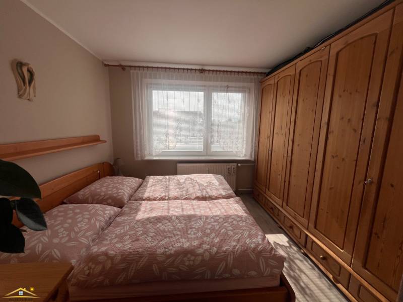 A bedroom in a 3-room apartment with a large wooden wardrobe and a bed.