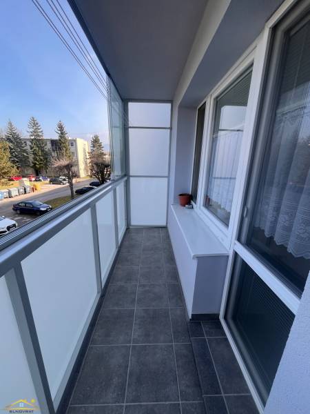 The balcony of a 3-room apartment in Rajec with dark tiles and a view of a well-maintained street.