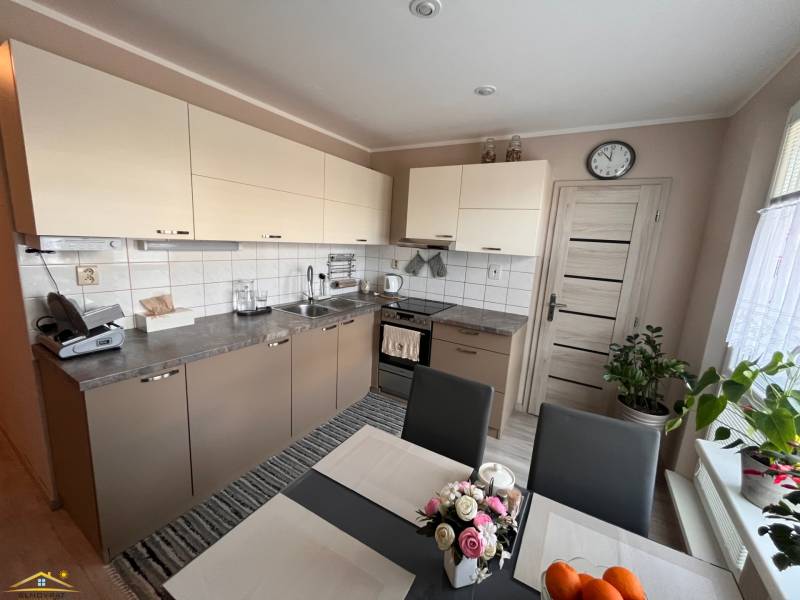 A kitchen in a 3-room apartment with light cabinets and a dining table.
