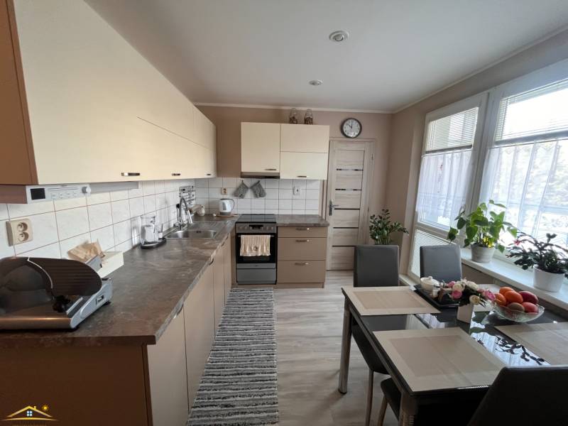 A kitchen in a 3-room apartment with a table, appliances, and plants.
