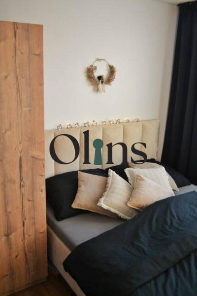 Bedroom in a 3-room apartment with a decorative wreath and black curtains; bed with pillows.