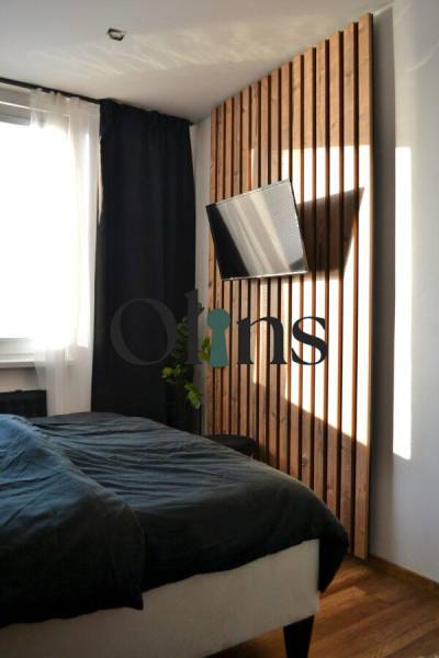 A bedroom with a TV and a wooden decor floor in a 3-room apartment.