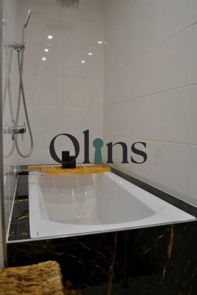 Bathroom in a 3-room apartment with a bathtub, showerhead, and white tiles.