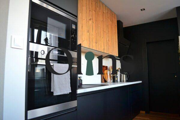 A kitchen in a 3-room apartment with black cabinets and a built-in oven, floor with wood decor.