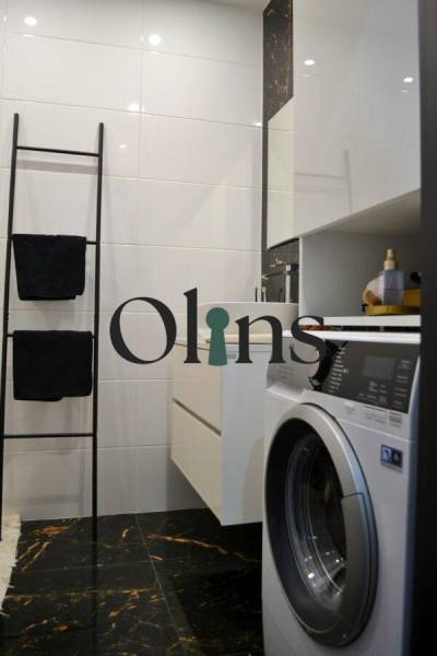Bathroom in a 3-room apartment with a washing machine, ladder towel rack, and white walls.