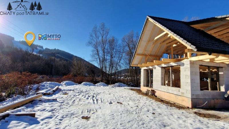 A winter construction of a cottage by the street in Mýto pod Ďumbierom in a snowy landscape.