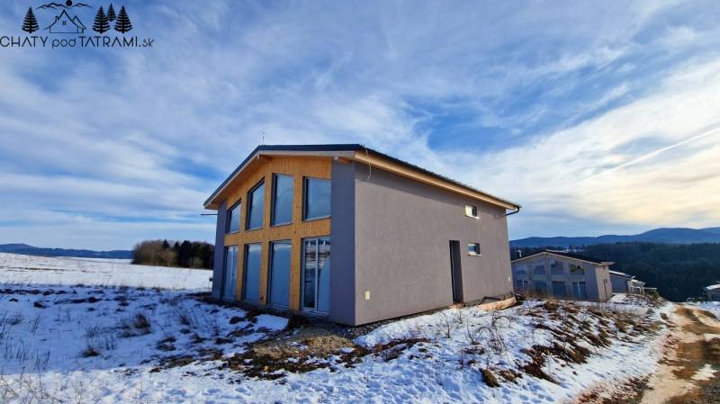 A cottage on a snowy street in Dolná Lehota with a view of the forests and mountains.