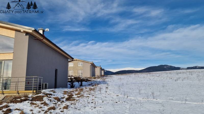 A cottage in a snowy field with a view of the mountains in Dolná Lehota.