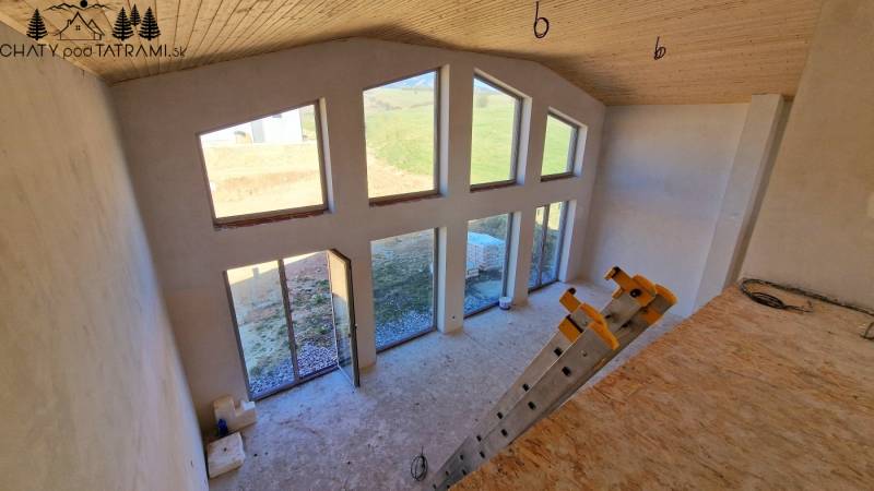 The interior of the cabin with large windows, steps, and a floor with a wooden decor.