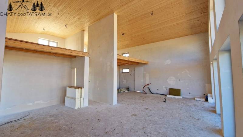 The interior of the cabin with a high ceiling, roughly finished walls, and delicate wooden decorations.
