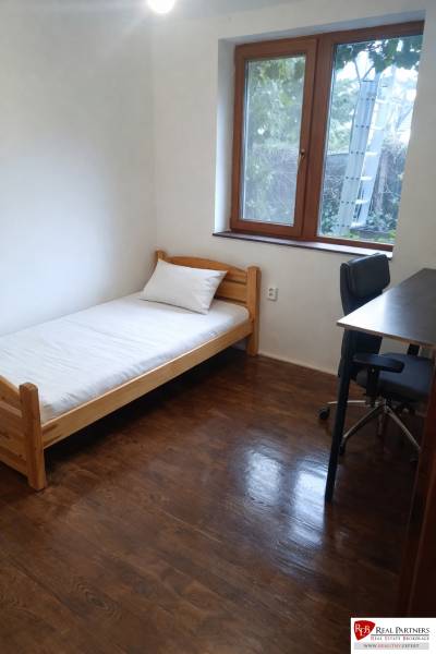 A simple room with a bed, a table, and a wooden floor decor in a 3-room apartment.