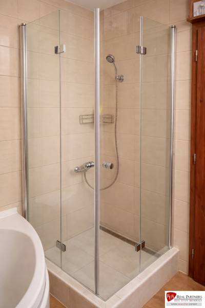 A shower corner in a 3-room apartment with a simple design and light tiles.