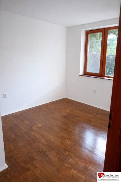 A room with wooden decor, white walls, a window, without furniture in a 3-room apartment.