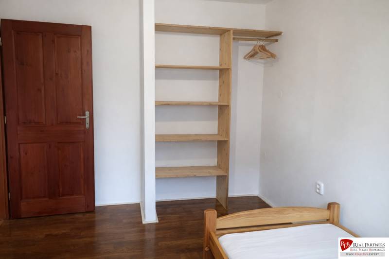 A bedroom with wooden decor, a built-in wardrobe, and a bed in a three-room apartment.