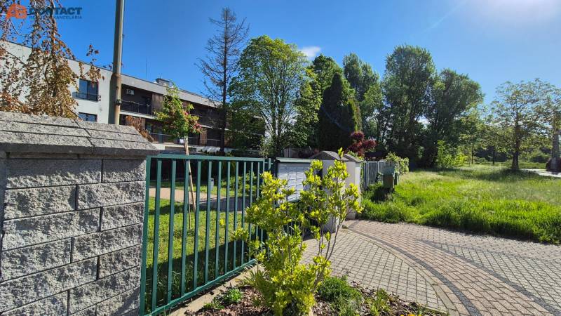 The garden by the building with a brick fence on Bodona Street, near the studio apartment, trees in the back.