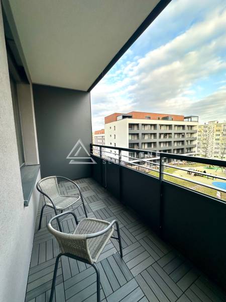 Balcony with two chairs and wood-patterned tiles, view of buildings.