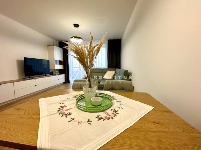 Living room in a 2-room apartment; sofa, television, table with decoration, floor with wooden decor.