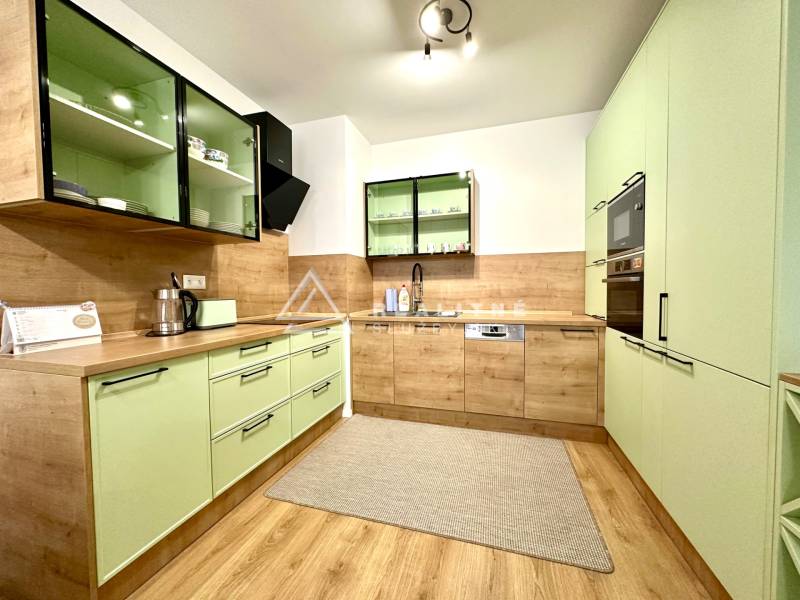 A kitchen in a 2-room apartment with pastel cabinets and a wooden decor floor.
