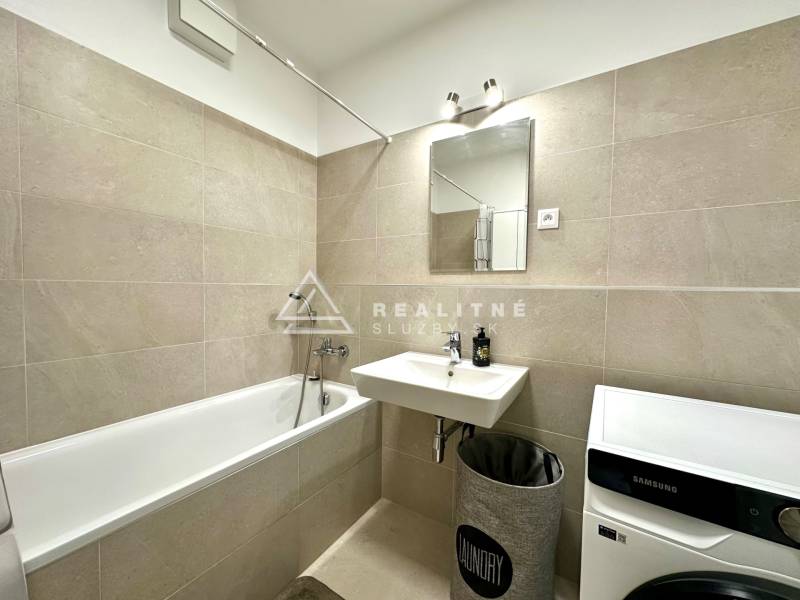 Bathroom in a 2-room apartment with a bathtub, sink, and washing machine.