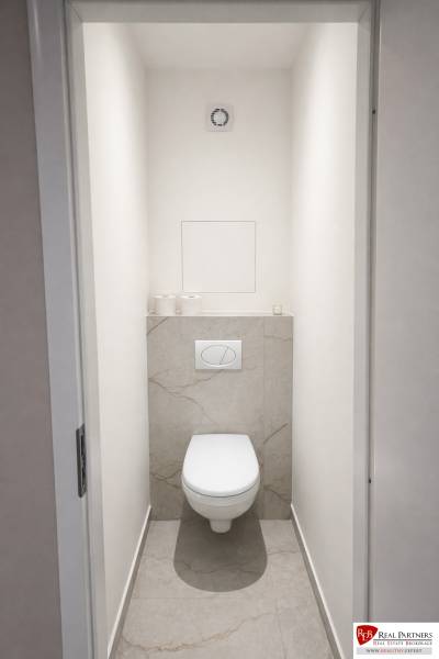 A toilet with a wall-hung bowl and simply styled tiles in a 2-room apartment.