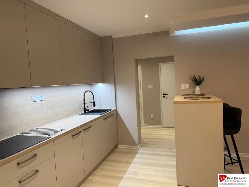 A kitchen in a 2-room apartment with a wooden decor floor and a kitchen unit.