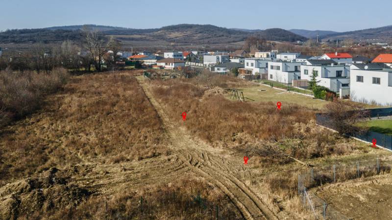 Land for residential use in Pezinok, surrounding houses, natural scenery, hills in the background.