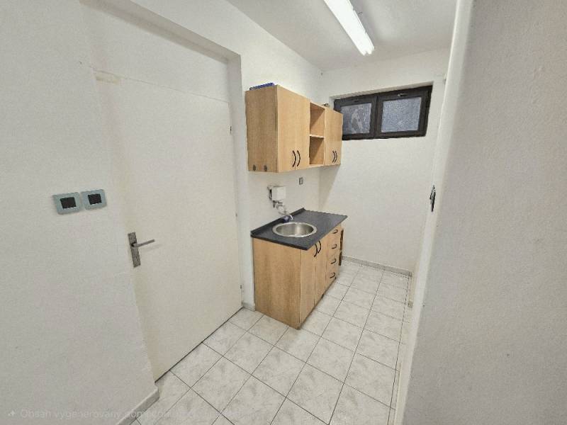 Kitchen corner with a sink and cabinets in commercial premises, tiled floor.