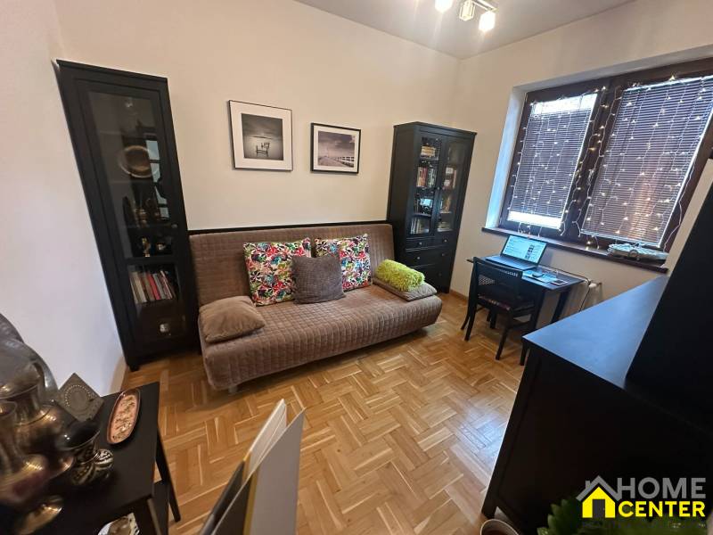Living room with a sofa and a desk in a family house with wood-patterned flooring.