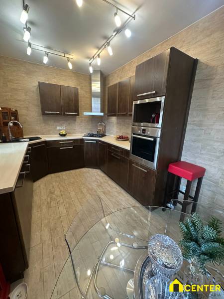 A kitchen in a family house with wooden floor decor and abundant lighting.