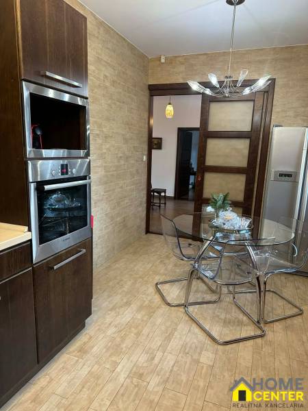 A kitchen in a family house with a wooden decor floor and a glass table.