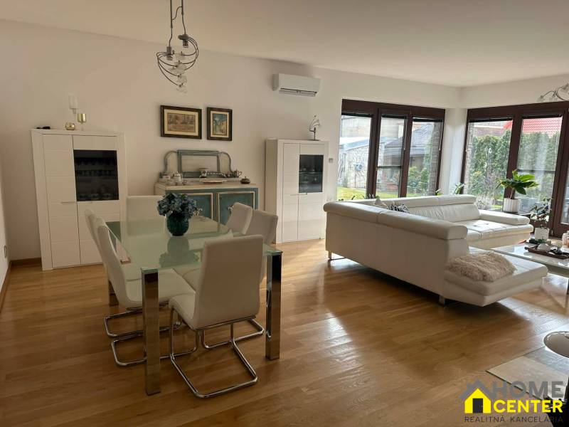 Living room in a family house with wood-patterned flooring and white furniture.
