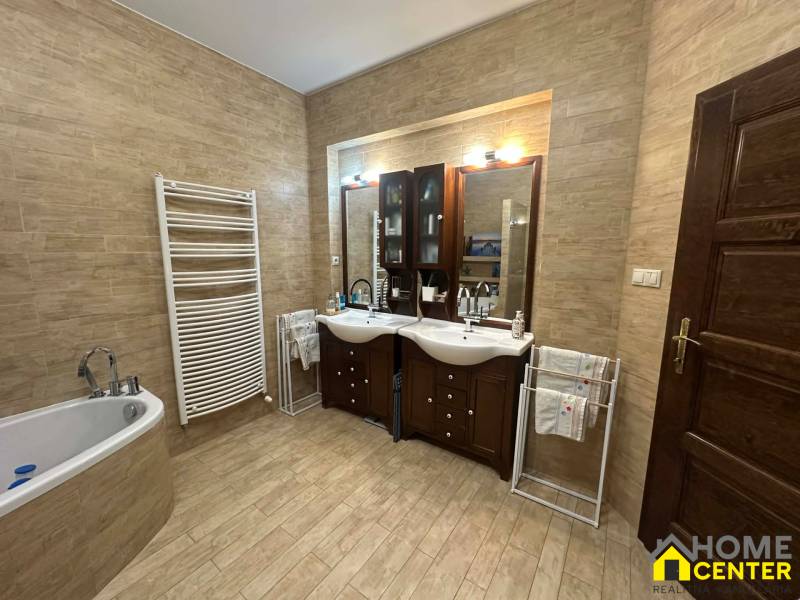 A bathroom in a family house with a wooden decor floor and two sinks.