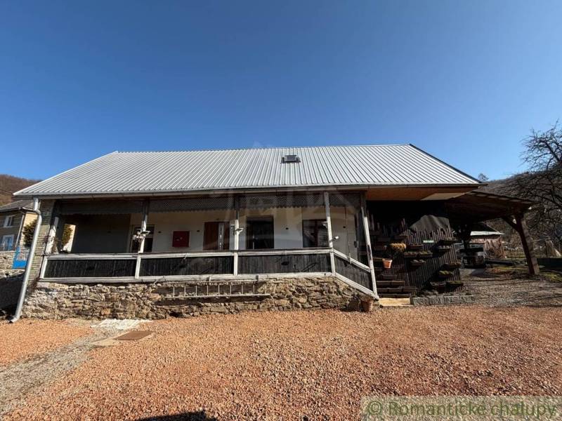 A family house in Ratkovské Bystré with a metal roof and a stone base in the garden.