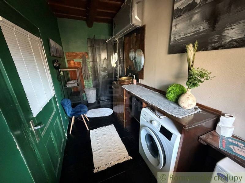 A bathroom in a family house with a wooden decor floor, washing machine, mirror, decorations.