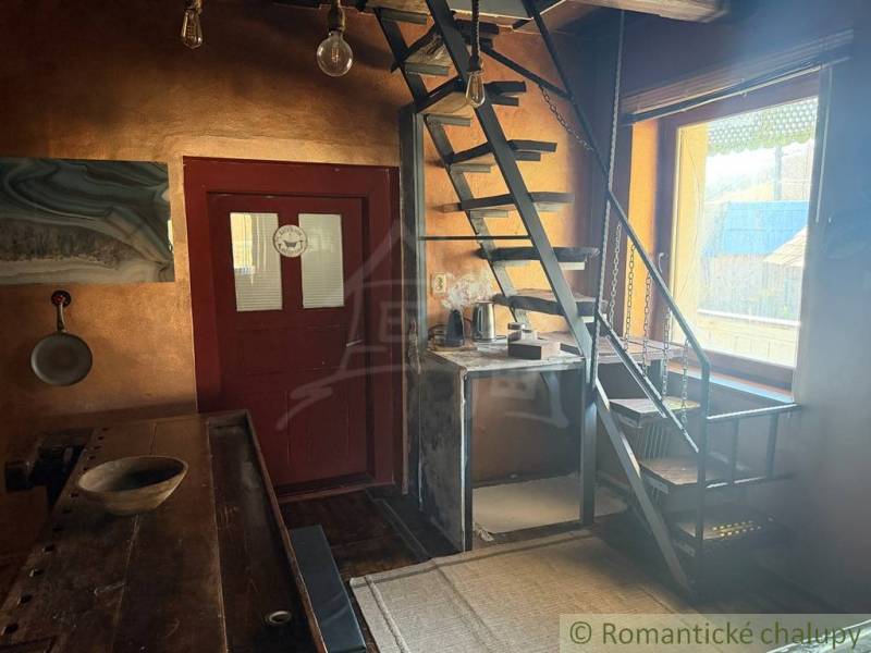 The interior of a family house with a metal staircase and a wooden table, light walls.