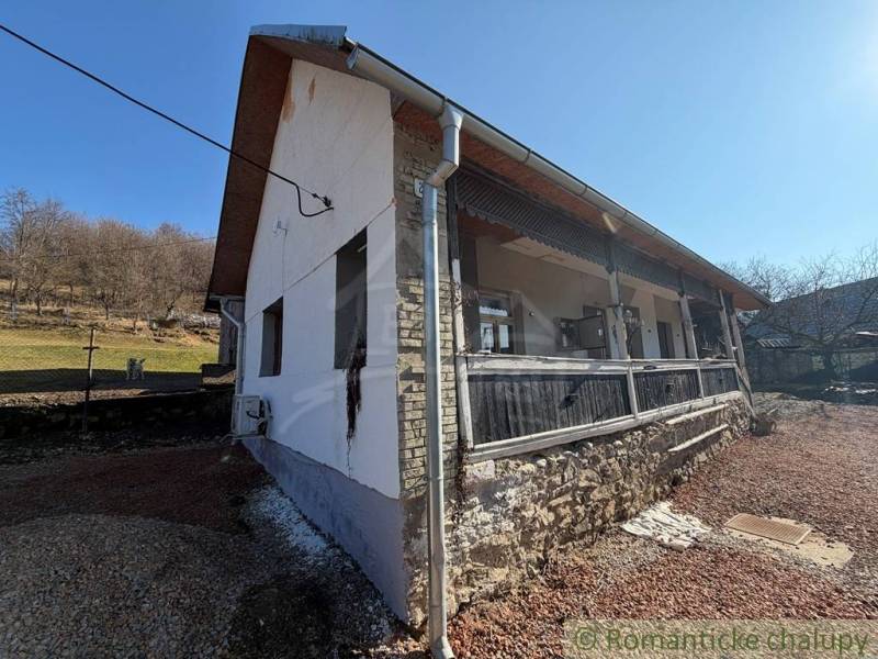 The exterior of a family house in Ratkovské Bystré with sunny weather and a stone base.