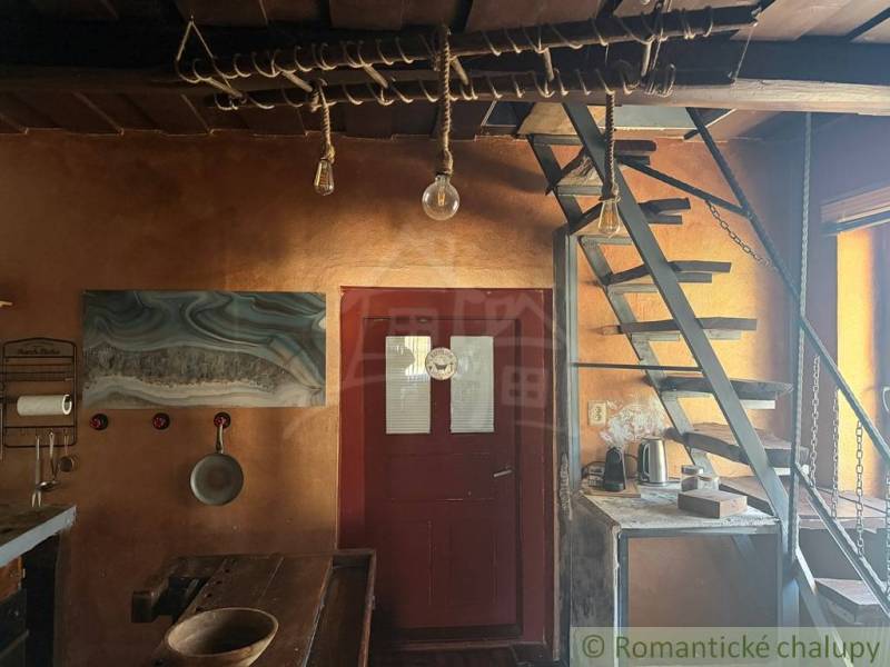 Interior of a family house with wooden stairs, a rustic table, and an artistic painting on the wall.